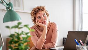 Eine Frau sitzt an ihrem Schreibtisch und guckt nachdenklich in die Luft.