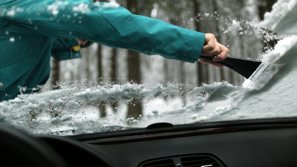 Eine Autoscheibe wird freigekratzt