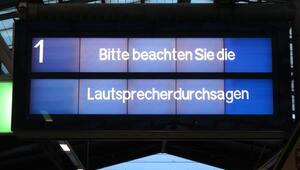 Bahnhofsschild mit Aussage: Bitte auf Lautsprecheransage warten. 