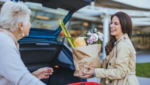 Frau hilft älterer Dame beim Einladen der Einkäufe 