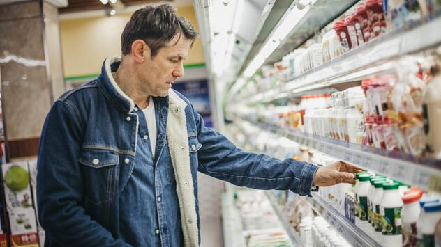 Mann in Supermarkt, der Preise vergleicht. 