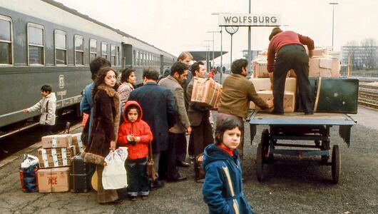 Eine Gruppe Menschen packt Koffer und Pakete auf einen Wagen
