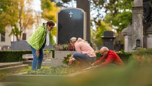 Menschen, die im Herbst am Grab auf dem Friedhof arbeiten.