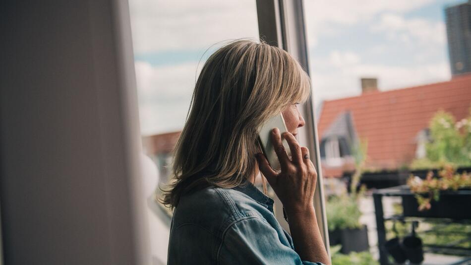 Eine Frau telefoniert am Fenster