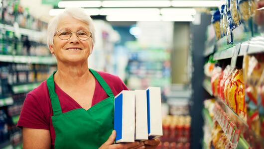 Foto einer Seniorin, die im Supermarkt arbeitet.