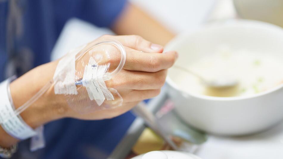 Person in Krankenhaus mit Infusion isst Suppe