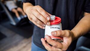 Ein Mann hält im Gym eine Packung Kreatin in seiner Hand