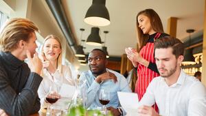 Kellnerin wartet auf Bestellung junger Gäste im Restaurant.