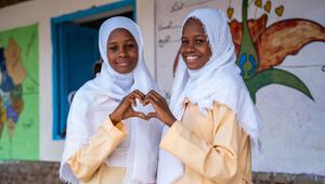 Zwei Mädchen formen ein Herz mit den Händen.