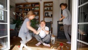 Gestresste Mutter sitzt zwischen dem Spielzeug ihrer Kinder