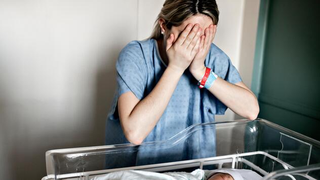 Eine Mutter am Bett mit ihrem Neugeborenen