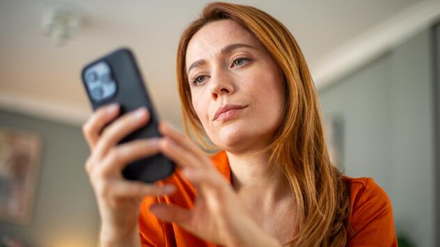Frau schaut genervt auf ihr Smartphone