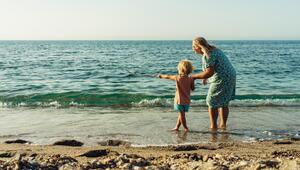 Ältere Frau und Kind schauen vom Strand aus aufs Meer