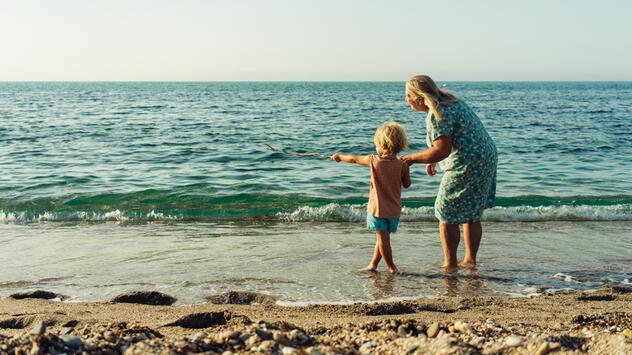 Ältere Frau und Kind schauen vom Strand aus aufs Meer