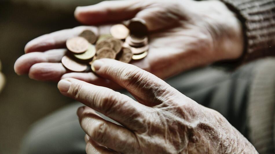 Ein älterer Mensch zählt Geldmünzen in seiner Hand