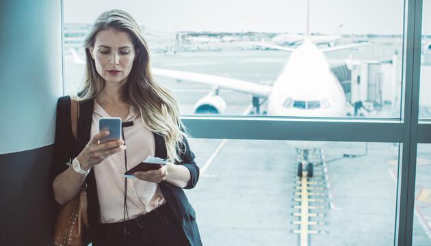 Frau mit Handy in der Hand am Flughafen