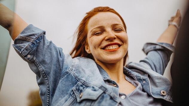 Frau, die sehr euphorisch die Arme hochwirft. 