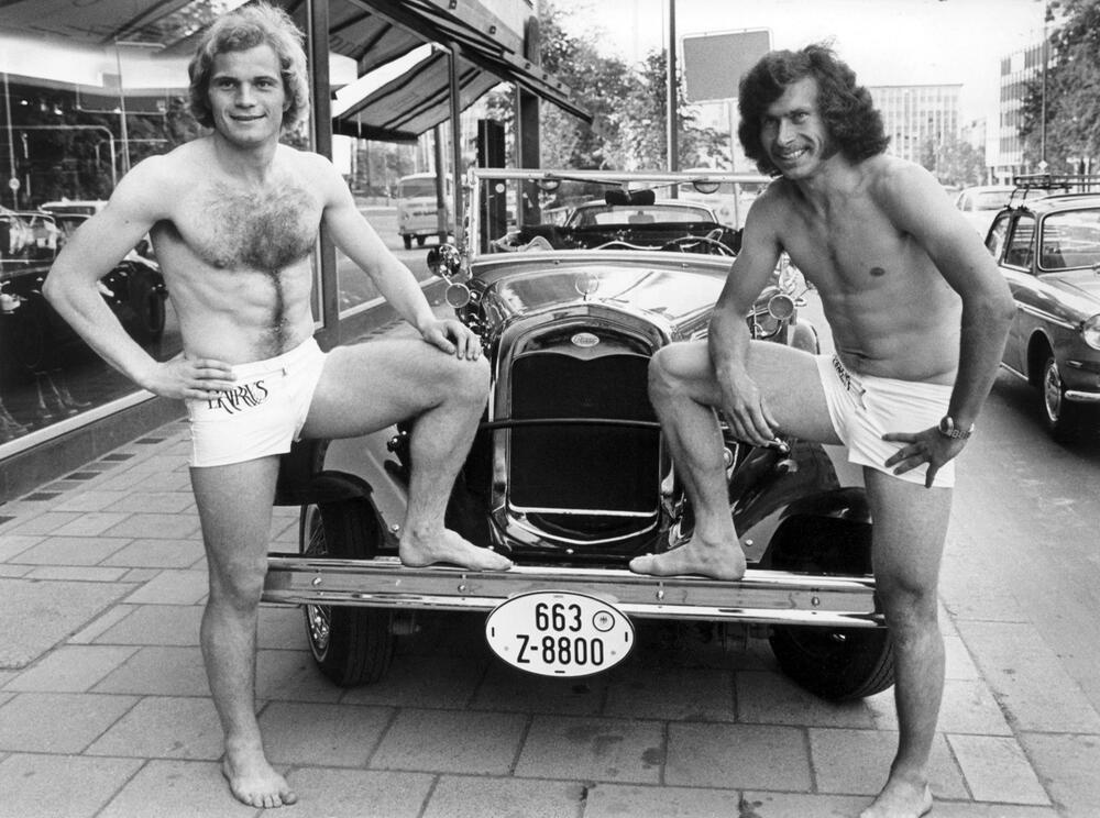 Uli Hoeneß und Paul Breitner in Badehose vor einem Oldtimer am 5. Juni 1973 in München