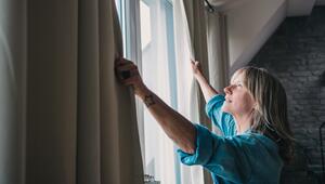 Eine Frau um die 50 schließt die Gardinen