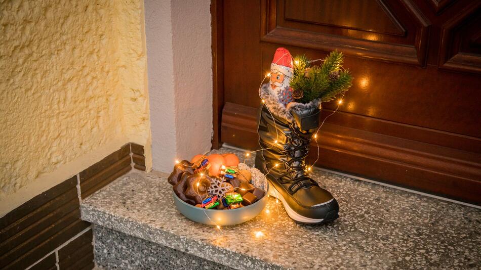 Mit Süßgkeiten gefüllter Stiefel steht zu Nikolaus vor einer Tür