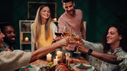 Gruppe Freunde stoßt beim winterlichen Essen mit Wein an