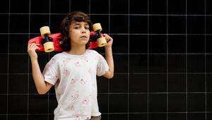 Selbstbewußter Junge trägt ein Skateboard auf seinen Schultern