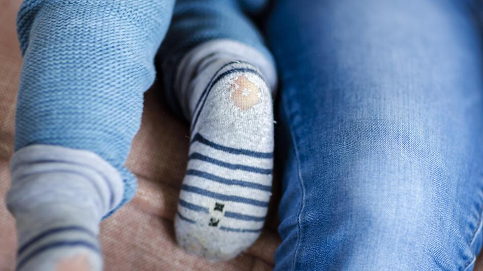 Kinderfüße mit kaputten Socken.