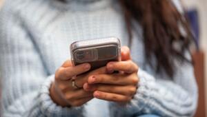 Eine junge Frau hält ein Smartphone in den Händen