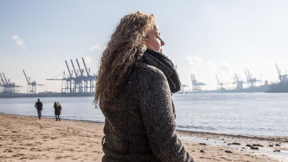 Eine Frau bei einem Spaziergang an der Elbe in Hamburg
