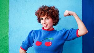 Eine FRau in einem blauen Pulli zeigt ihre Armmuskeln.