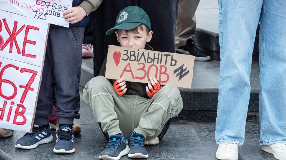 Ein kleiner Junge hält ein Schild in die Luft