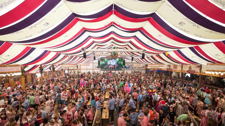Menschen feiern im Festzelt auf dem Cannstatter Wasen