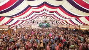Menschen feiern im Festzelt auf dem Cannstatter Wasen