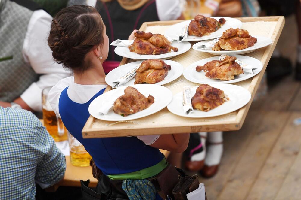 Bedienung trägt in einem festzelt ein Tablett mit Wiesn-Hendln