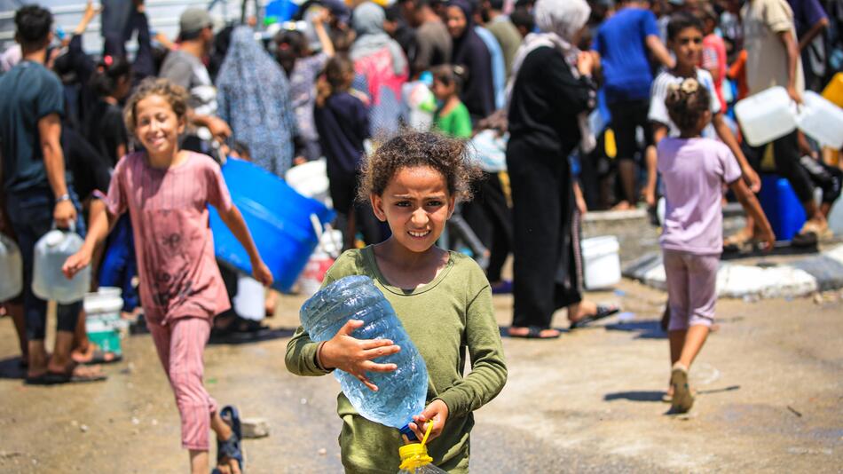 Ein Kind in Gaza hält zwei große Wasserkanister in der Hand