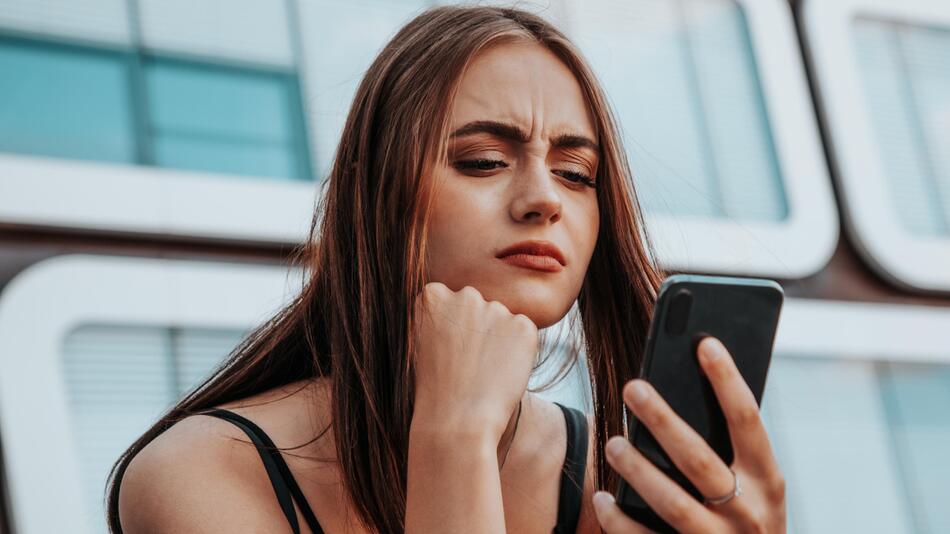 Frau blickt kritisch auf Smartphone