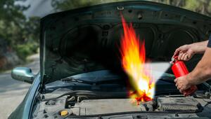 Auto mit offener Motorhaube, Flammen und ein Mensch mit Feuerlöscher