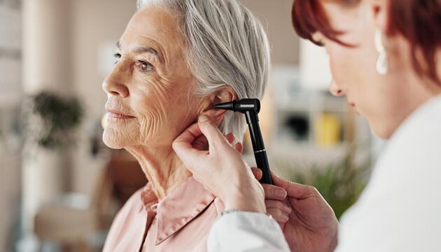 ältere grauhaarige Frau mit Hörgerät in Seitenansicht