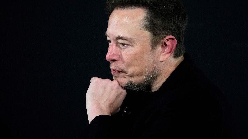 Elon Musk sitzt und denkt nach.