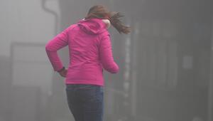 Frau kämpft auf dem Großen Feldberg im Taunus gegen Wind an