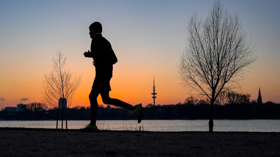 Ein Jogger läuft an der Alster entlang