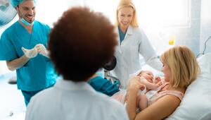 Männliche Hebamme mit Ärztinnen nach Geburt eines Babys am Krankenbett