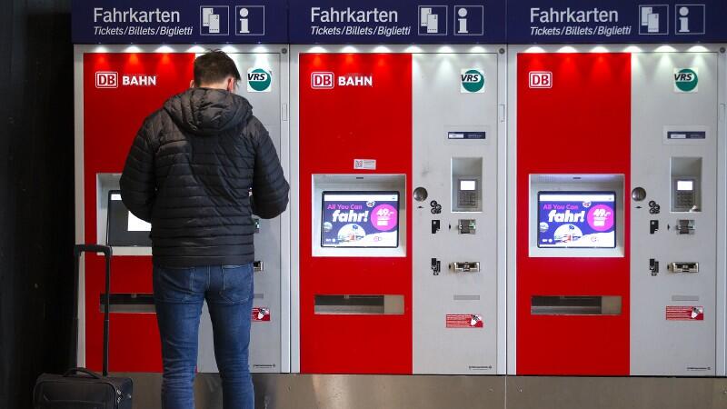 Ein Mann steht vor einem Fahrkartenautomat.