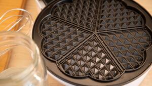 Waffeleisen mit Teigresten steht auf einem Tisch
